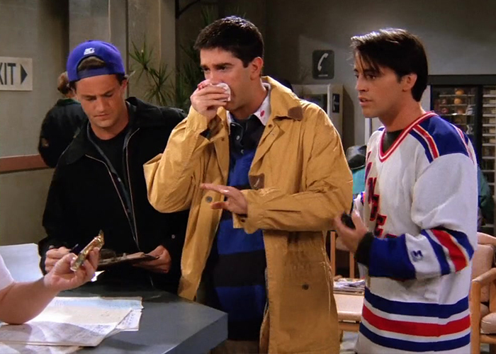 Ross, Chandler, and Joey at a hockey game, with Ross holding his face after getting hit by a puck.