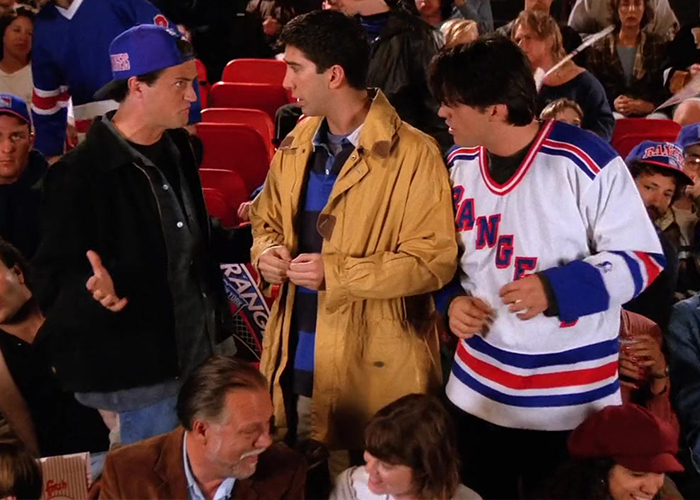 "Ross, Chandler, and Joey at a hockey game, with Ross holding his face after getting hit by a puck."