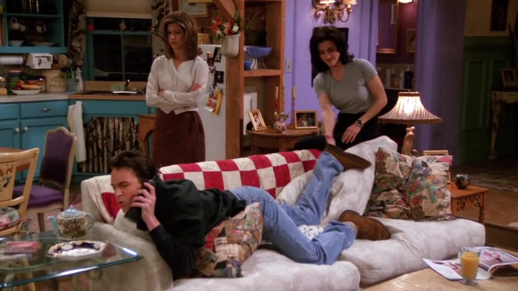 Film-based language learning - Chandler lying on the couch while Monica and Rachel interact in Friends S01E20"