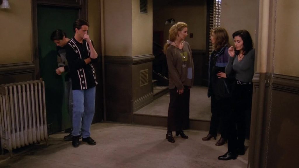 Monica, Chandler, Phoebe, Rachel, and Joey standing in the apartment hallway in Friends S01 E09.