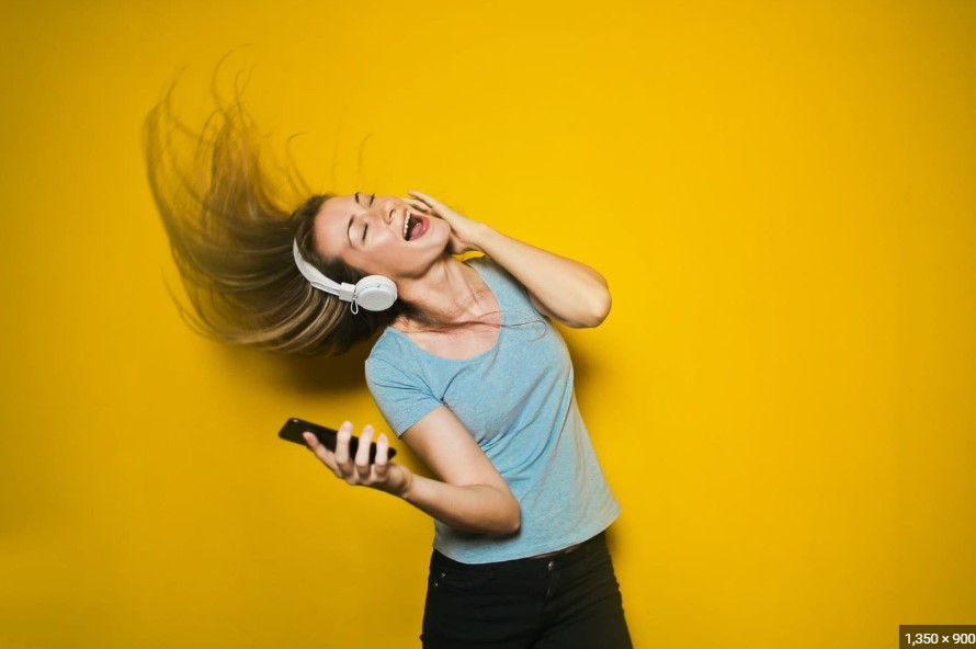 A woman joyfully listening to a Spotify podcast, learning languages with enthusiasm.