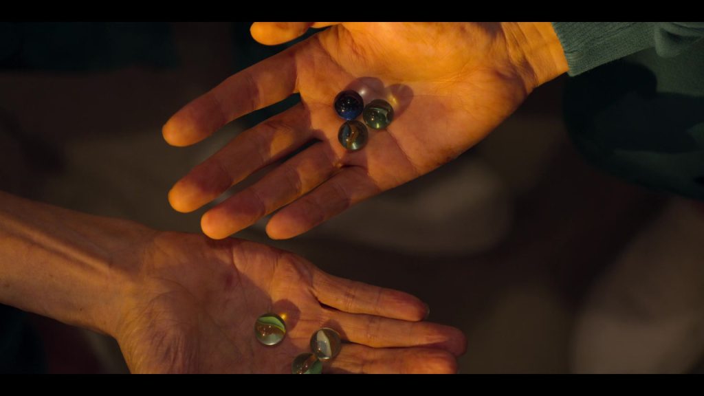 Two hands holding marbles, symbolizing trust and tension.