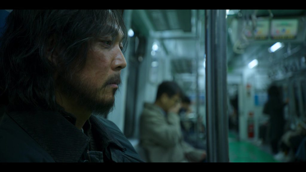 Gi-hun on the subway, reflecting during Squid Game final episode, movie vocabulary learning.