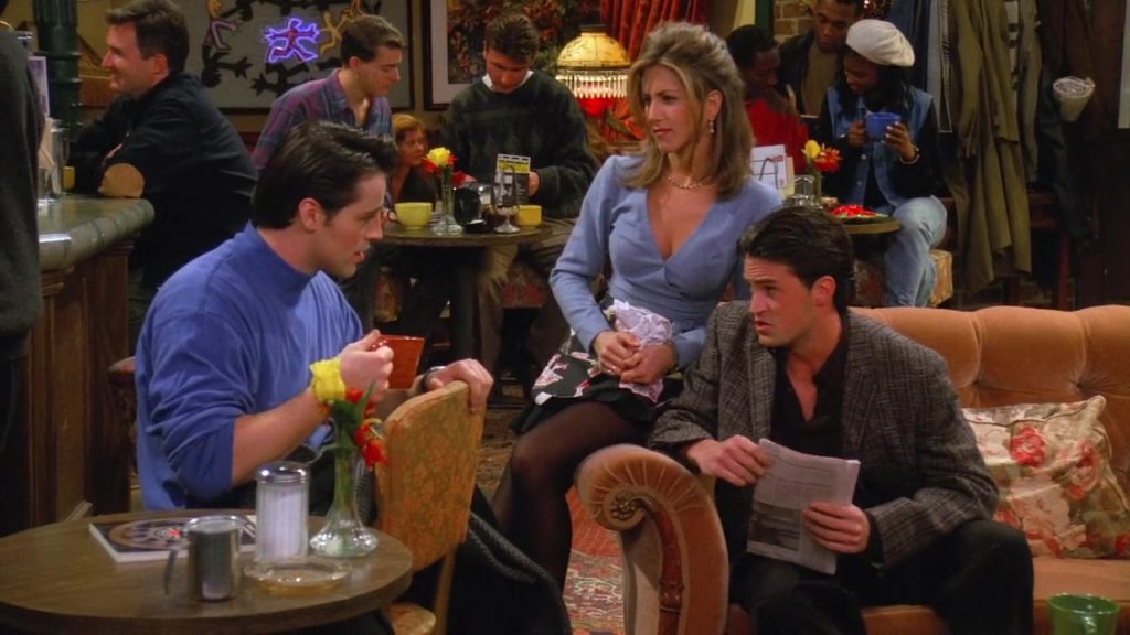 Joey, Rachel, and Chandler sitting at Central Perk in Friends, discussing Thanksgiving plans.