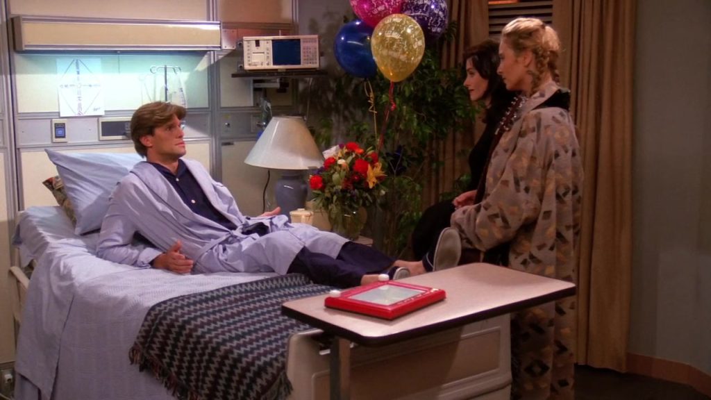 Ross and a blonde woman standing together at a bar scene in Friends.