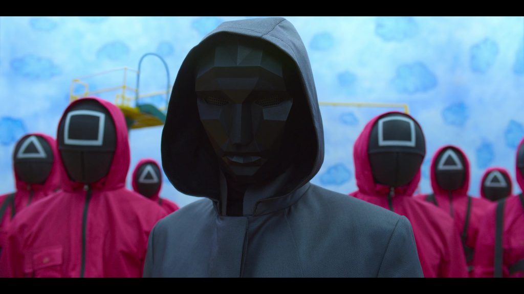 Language Learning with Netflix - Masked Guards and Leader Scene Masked guards and their leader in a chilling scene from Squad Game.