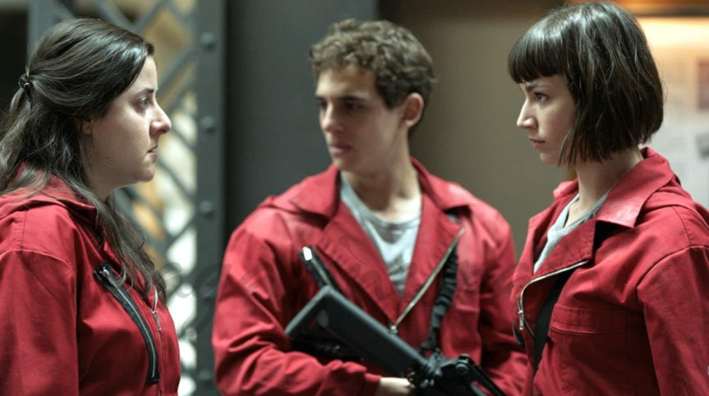 Three Money Heist characters in red jumpsuits having a serious discussion.