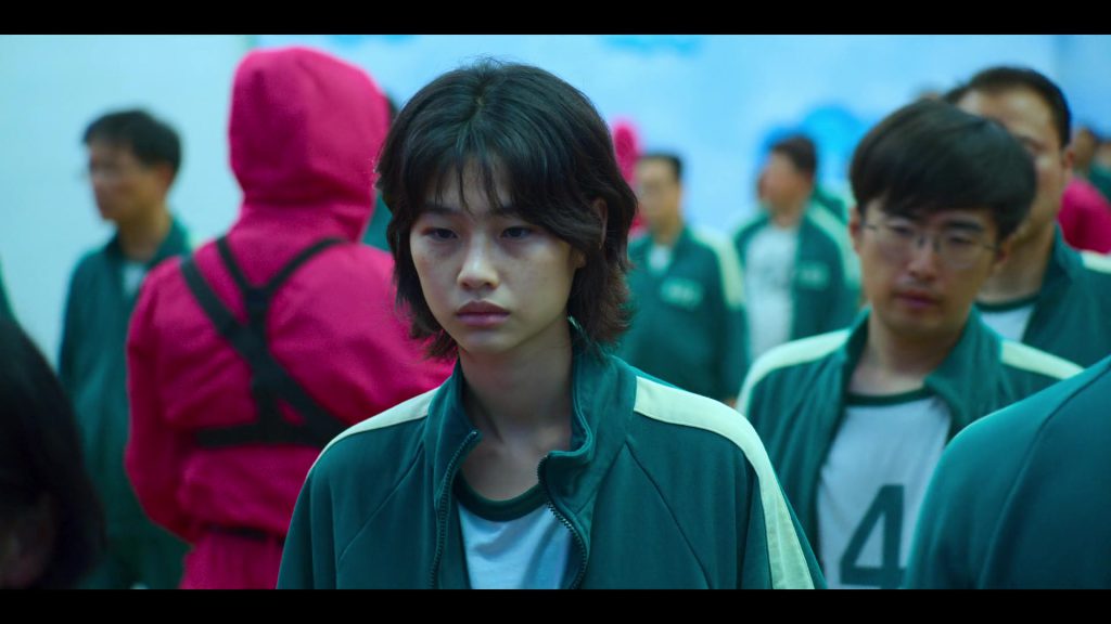 Language Learning with Netflix - Engaged Character Scene Determined player in green uniform during a tense moment in Squad Game.