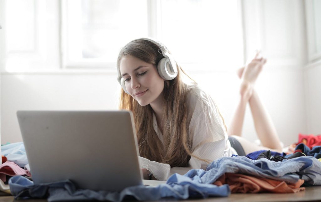 Woman with headphones studying on her laptop, practicing language learning with podcasts.