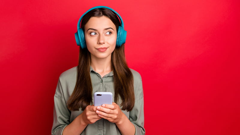Woman with headphones studying on her laptop, practicing language learning with podcasts.