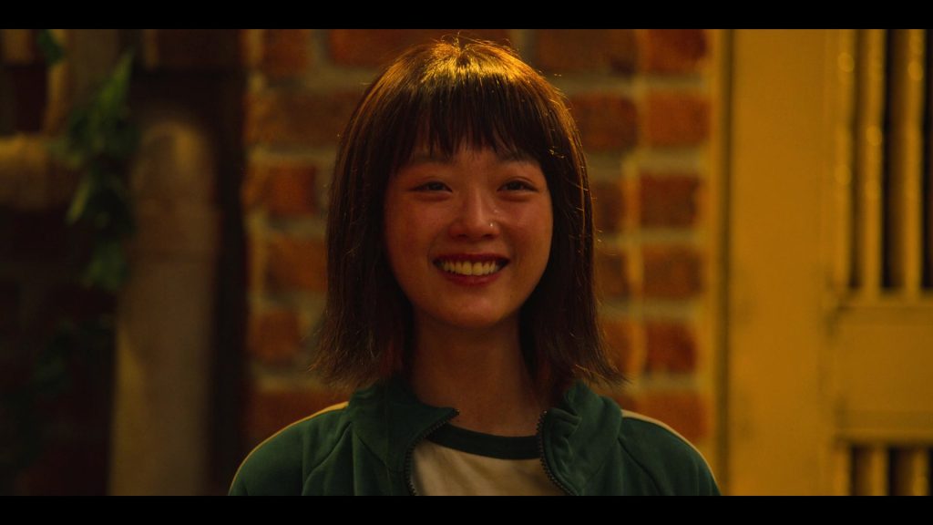 A female contestant smiling in an emotional, tearful moment in Squad Game.