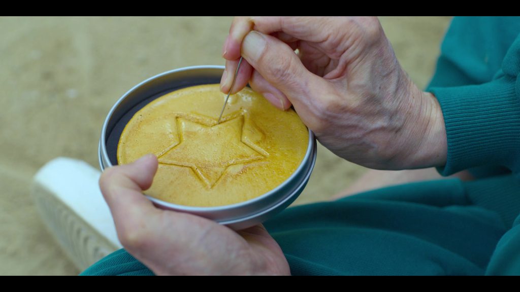 Learn English Through Movies - Sugar Honeycomb Challenge Close-up of hands carving a honeycomb candy in Squad Game.