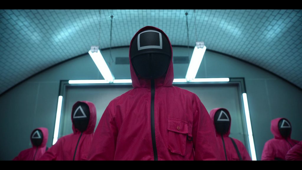 Masked enforcers in red uniforms from Squid Game Season 1 Episode 2.