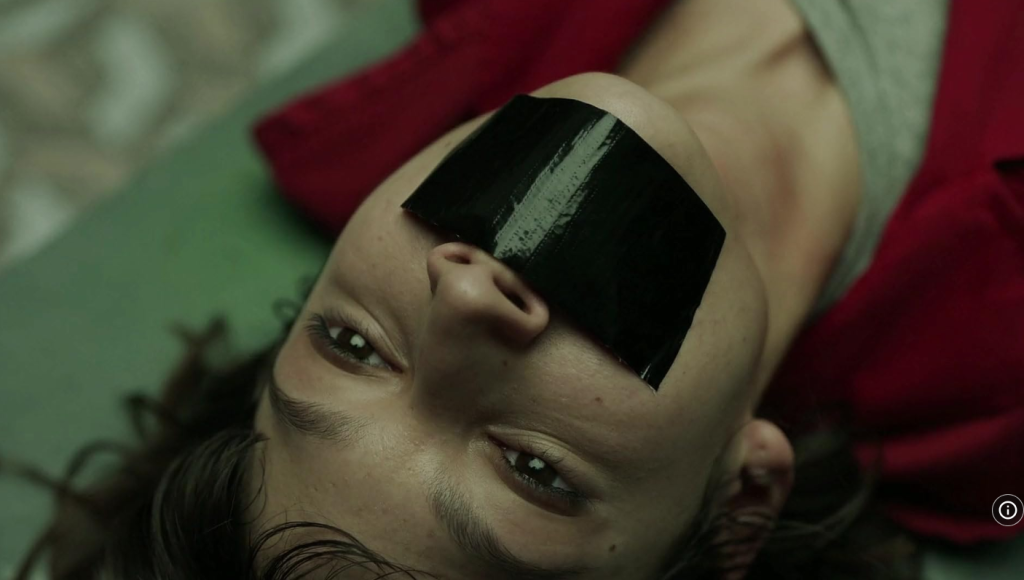 A hostage with their mouth taped shut from Money Heist S01 Part 02 E11, illustrating dramatic vocabulary for movie for language learning.