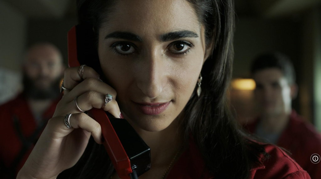 Close-up of a character in Money Heist S01 Part 02 E11 holding a red phone, representing tension and betrayal in movie vocabulary learning.