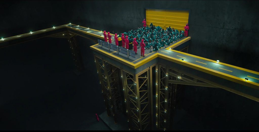 Players in Squid Game gathered on a high platform with masked guards, perfect for learning vocabulary about suspense and survival."