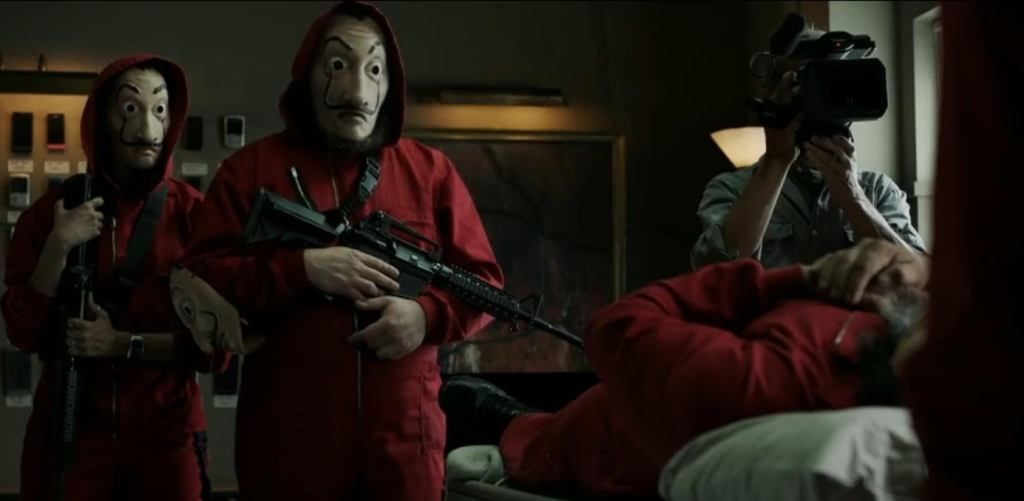 Characters in Money Heist wearing Salvador Dalí masks and red jumpsuits, holding rifles during a tense scene.
