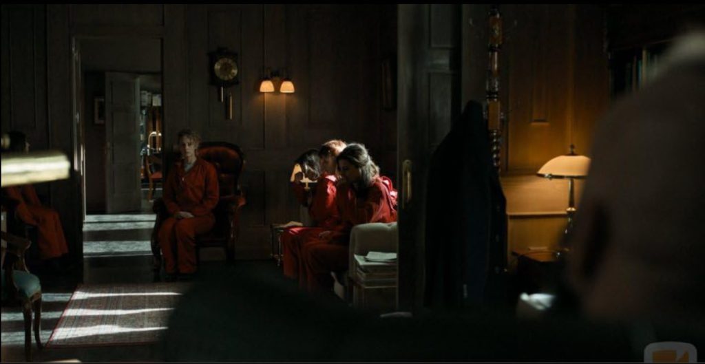 Captives sitting in red overalls in Monet Heist for Netflix language lessons.