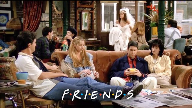  "The Friends cast sitting at Central Perk as Rachel Green stands in a wedding dress in Season 1 Episode 1."