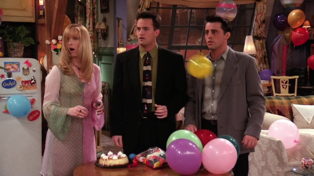 Phoebe, Chandler, and Joey preparing for Rachel’s birthday party in Friends S02E22. Learn vocabulary in a fun context.