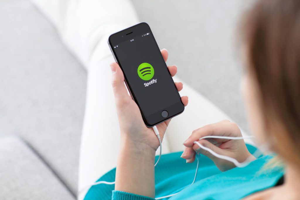 Woman holding a phone displaying the Spotify app interface