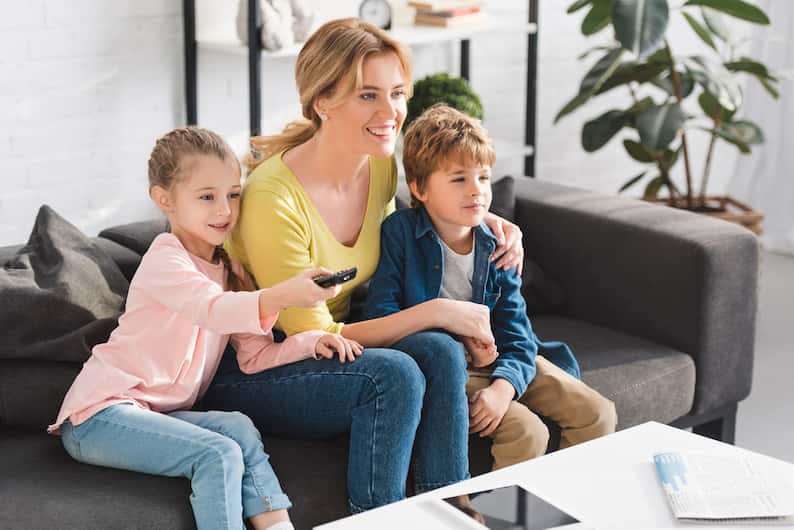 A family sitting on a couch watching TV together, symbolizing the role of media in shaping accents.