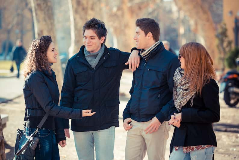 A group of friends chatting outdoors in winter clothing, symbolizing regional diversity in accents.