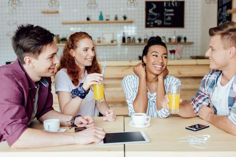 A group of young adults enjoying drinks in a modern café, symbolizing language learning and American English.