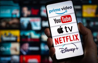 Hand holding a phone showing streaming apps like Netflix, YouTube, Disney+, Apple TV, and Prime Video